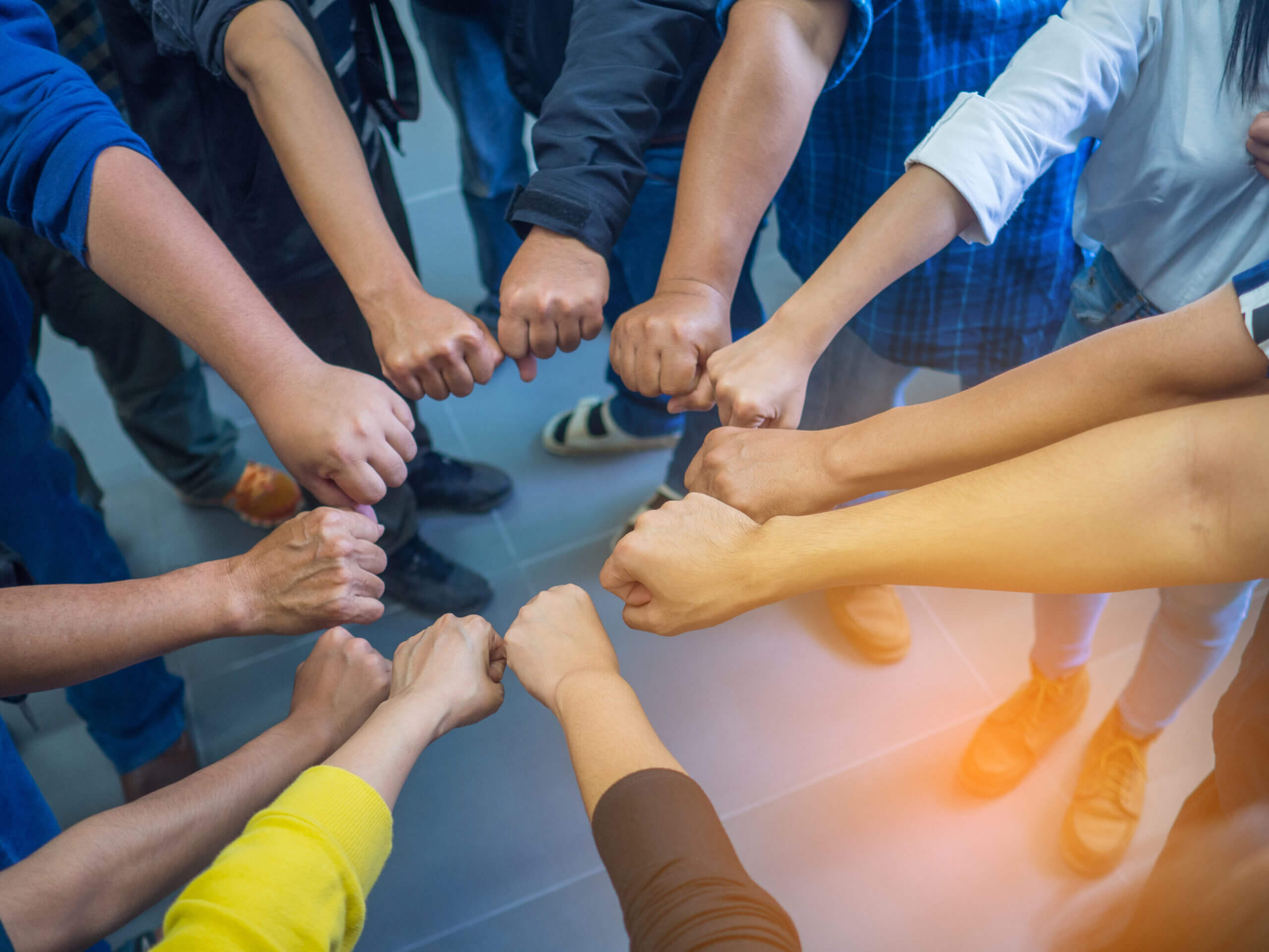 Close-up of many people putting their fists together as symbol o